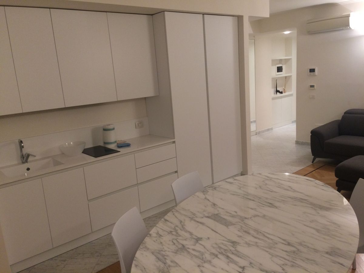 Cucina e soggiorno di un appartamento a Viareggio con arredi bianchi su misura